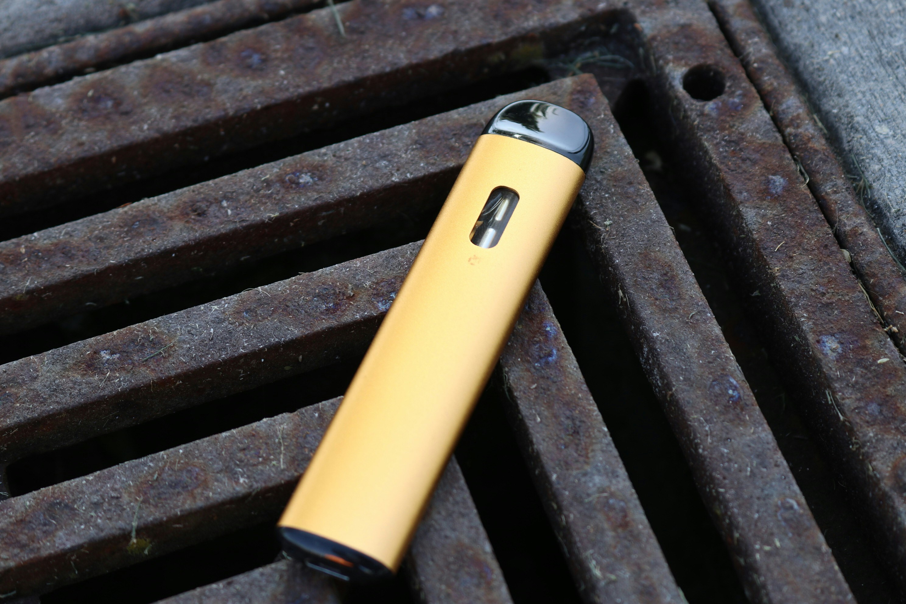gold vape pen on a metal grate