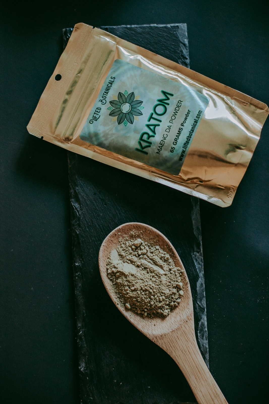 bag of the Maeng Da kratom strain powder next to a wooden spoon